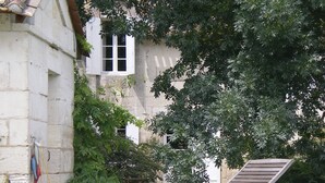 A poolside area with a lounge chair, a stone building, and lush greenery. - A haven of tranquillity on the banks of the Dordogne River (Fronsac)