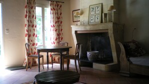 A cozy living room with a fireplace, a dining table with chairs, and a patterned rug. - A haven of tranquillity on the banks of the Dordogne River (Fronsac)