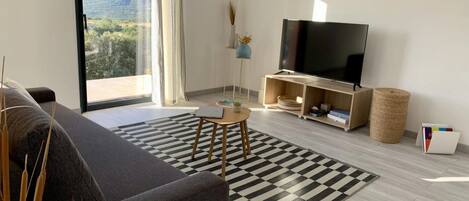 A modern living room with a large flat-screen TV, a sofa, a small table, and a checkered rug.