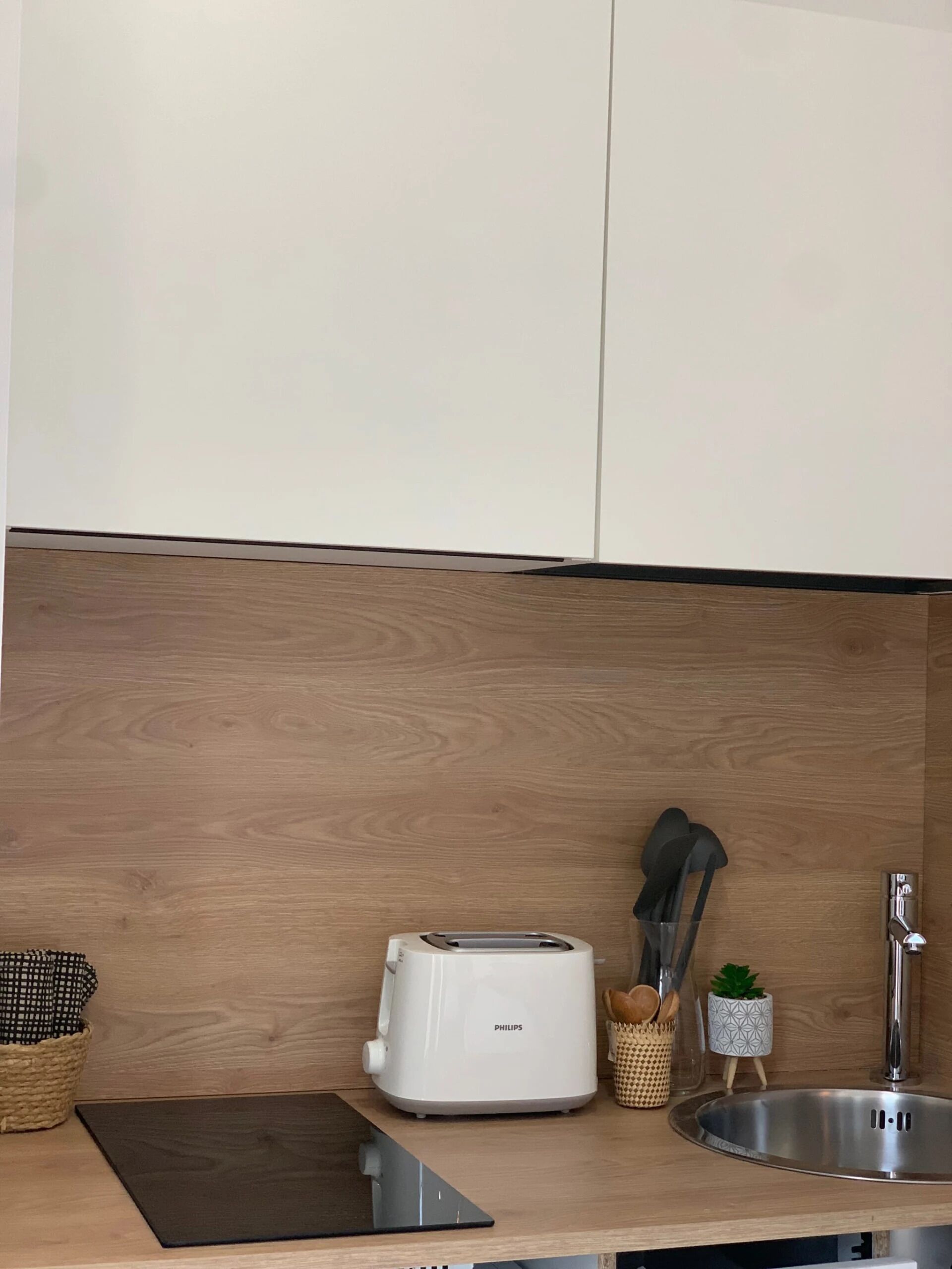 A kitchen with a white toaster, a sink, and a tablet on the counter.