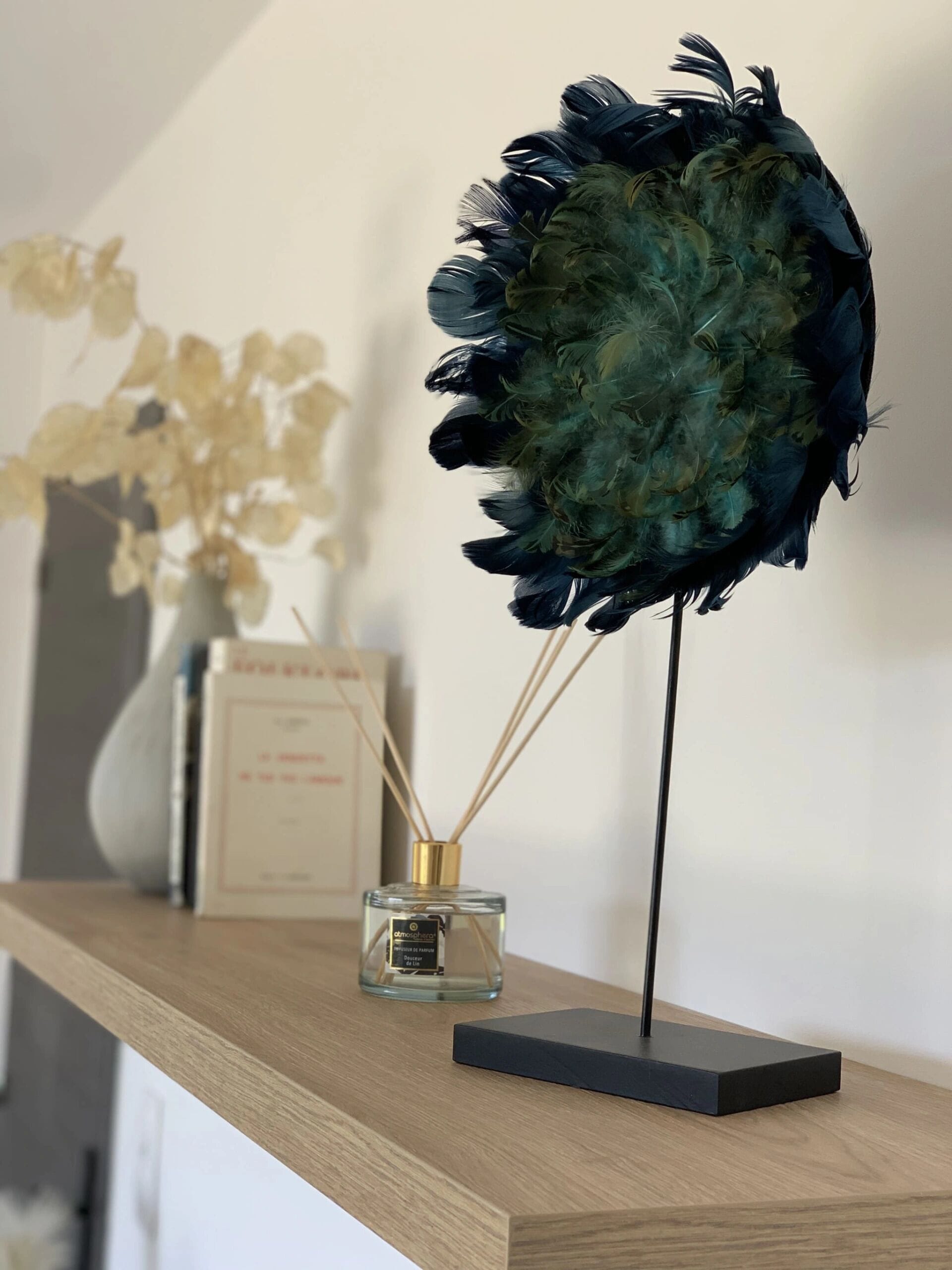 A display of feathers on a stand with a perfume bottle beside it.
