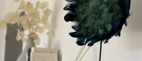 A display of feathers on a stand with a perfume bottle beside it.
