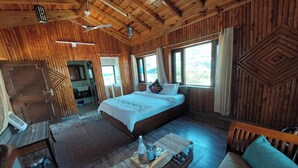 A wooden cabin bedroom with a bed, bedside table, and a window with curtains. - Alinda House Naukuchiatal by THE GHAUR (Uttarakhand)