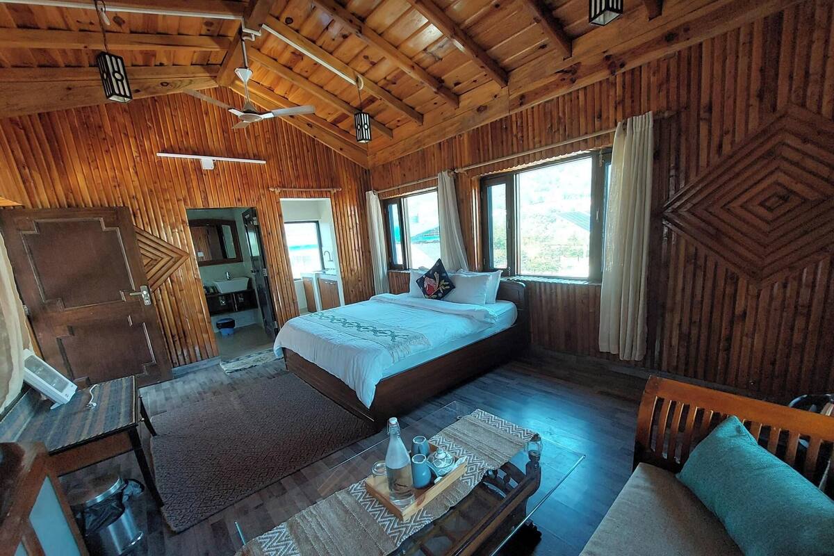 A wooden cabin bedroom with a bed, bedside table, and a window with curtains.