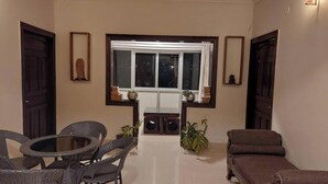 A room with a dining table and chairs, a sofa, a window with curtains, and a ceiling fan. - Alinda House Naukuchiatal by THE GHAUR (Uttarakhand)