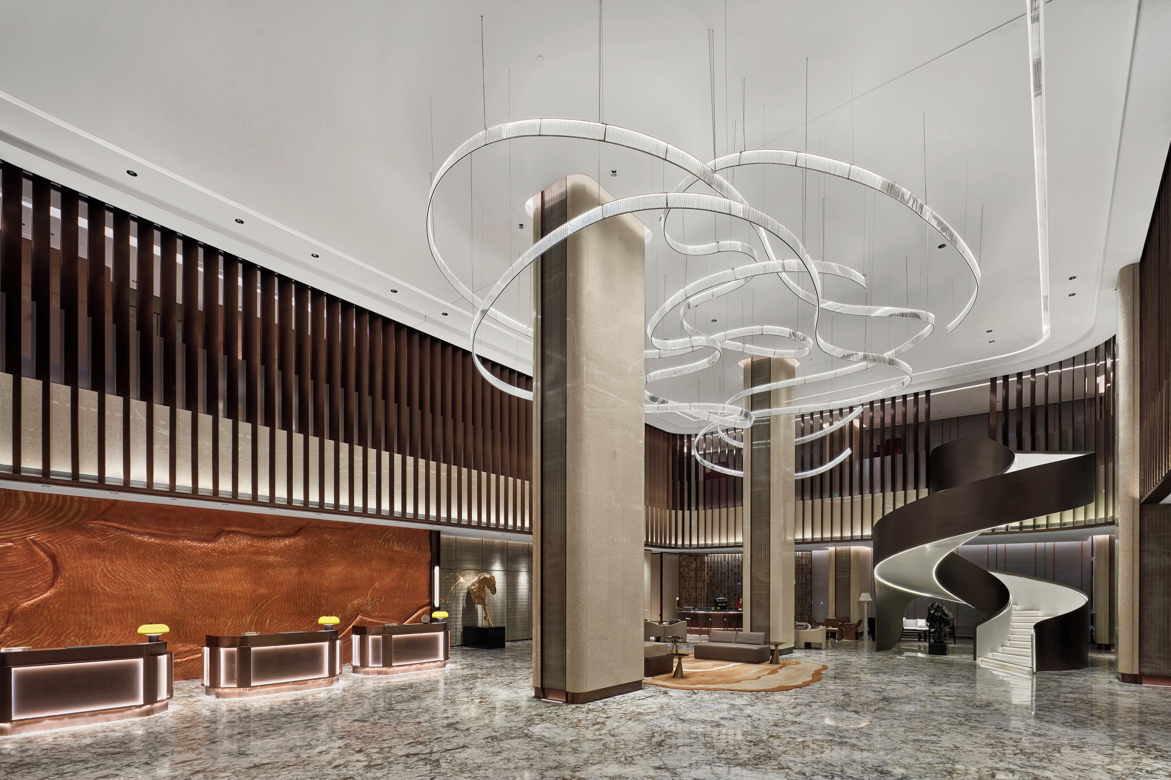 Un vestíbulo moderno con una escalera espiral central, un mostrador de recepción y paneles de madera.