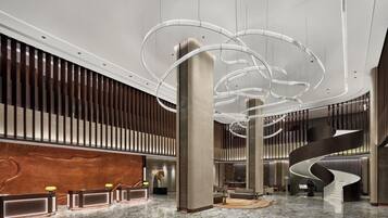 Un vestíbulo moderno con una escalera espiral central, un mostrador de recepción y paneles de madera.