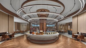 Un hall d’entrée spacieux doté d’un comptoir de réception circulaire central, d’un revêtement de sol en bois et d’un éclairage moderne.