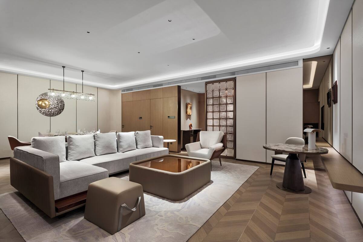 A modern living room with a sectional sofa, a coffee table, and a dining area with a round table and chairs.