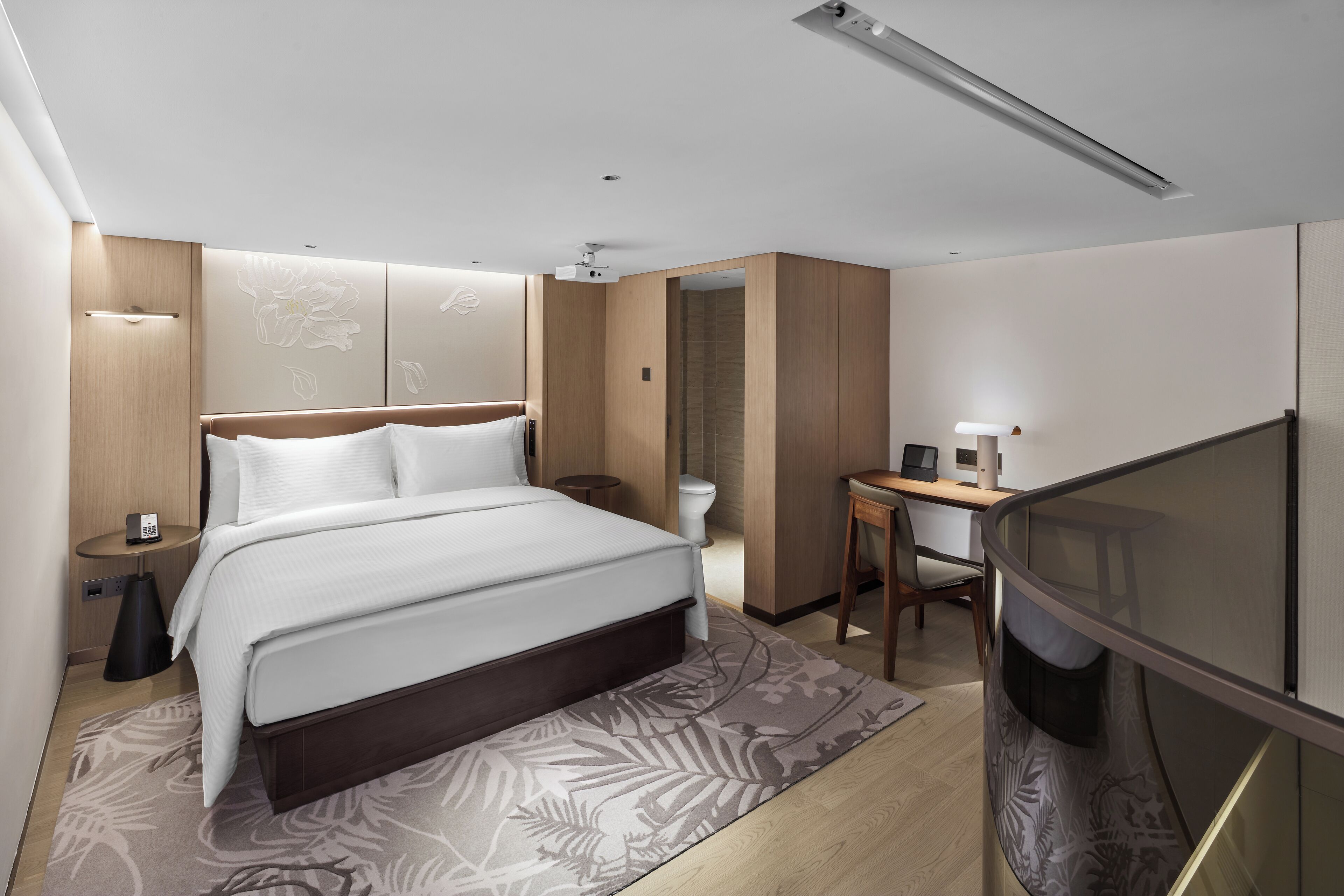 Una habitación de hotel moderna con una cama grande, un escritorio y una zona de estar.
