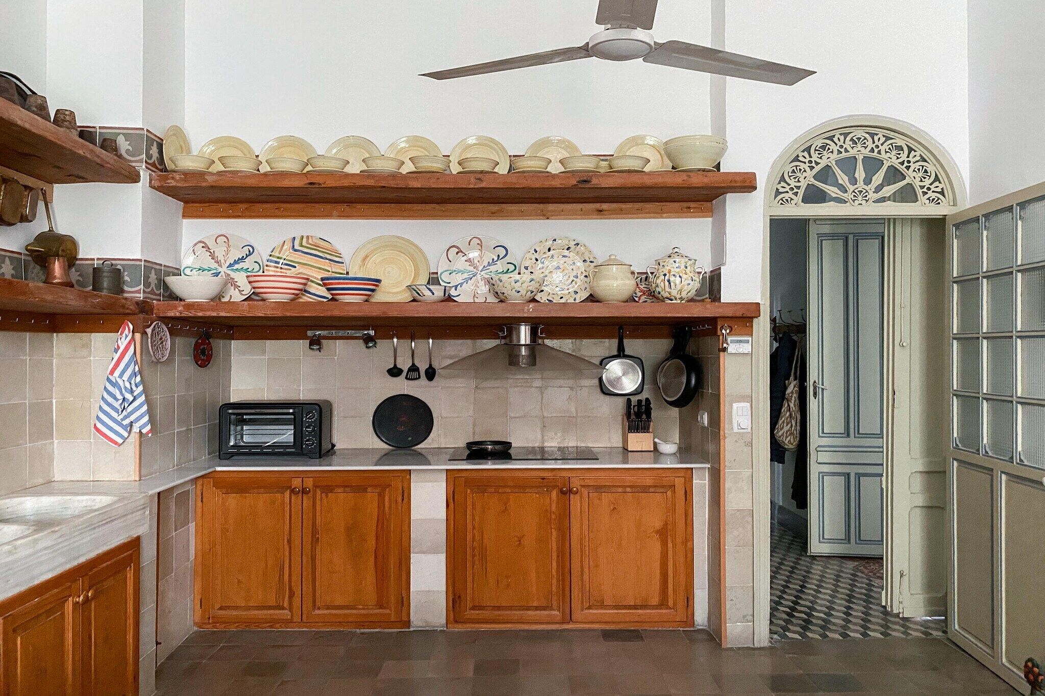 Eine Küche mit Holzausstattung, einer Mikrowelle und einem Deckenventilator.