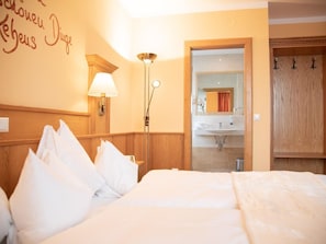 Ein Hotelzimmer mit Bett, Nachttisch, Lampe, Spiegel und einem Holzschrank.