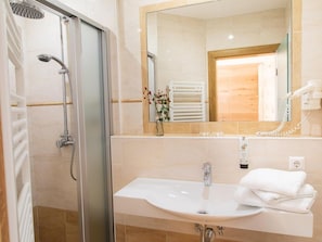Ein Badezimmer mit Duschkabine, Waschbecken mit Spiegel und Handtuchhalter.