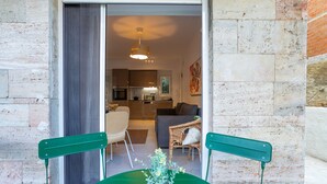 A modern interior with a dining area featuring a green table and chairs, a potted plant, and a view into a living room with a sofa and a dining table. - Renovated 2-bedroom Apt Near the Athenian Coast (Palaio Faliro)