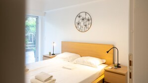 A neatly made bed with white linens, a bedside lamp, and a wall-mounted artwork. - Renovated 2-bedroom Apt Near the Athenian Coast (Palaio Faliro)
