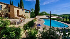 Eine Steinvilla mit Swimmingpool, Sitzgelegenheiten im Freien und Blick auf die Landschaft.