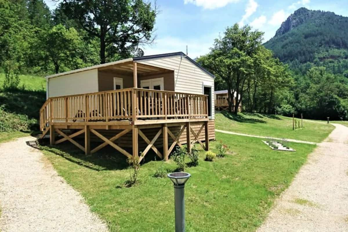 Eine Hütte mit einer Terrasse, umgeben von Wald und Bergen.