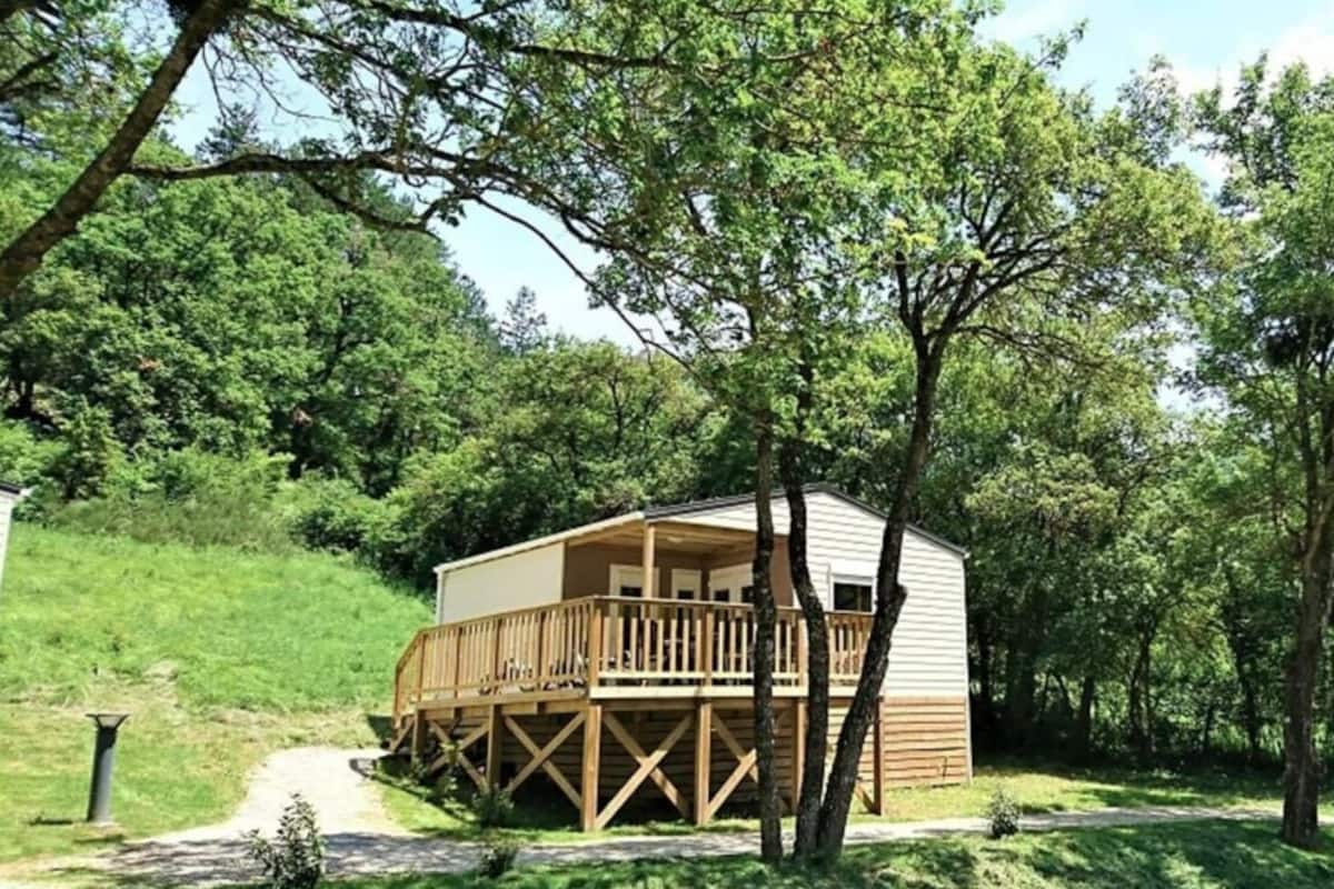 Eine eingeschossige Holzhütte mit einer Terrasse, umgeben von üppiger Vegetation und Bäumen.