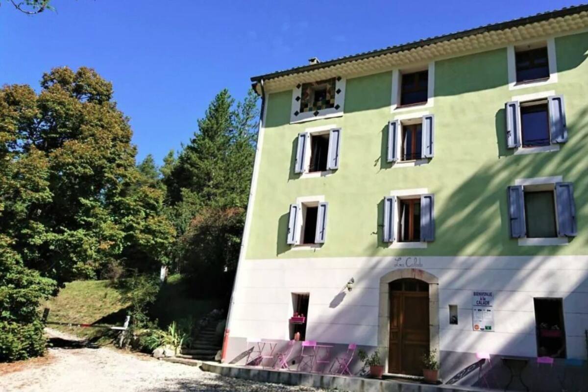 Ein mehrstöckiges Gebäude mit grüner Fassade, weißer Ornierung und zahlreichen Fenstern mit Fensterläden.