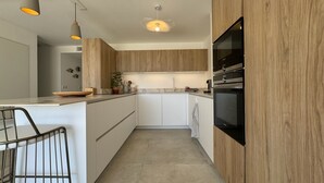 Una cocina moderna con armarios de madera, horno empotrado e iluminación colgante.