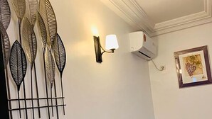 Et spiseområde med et sort marmorbord og hvide stole, en fastmonteret aircondition og dekorative billeder på væggen.