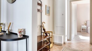 Een modern interieur met een zwarte console tafel, een houten bankje, een wandrek en een lijst met een afbeelding.