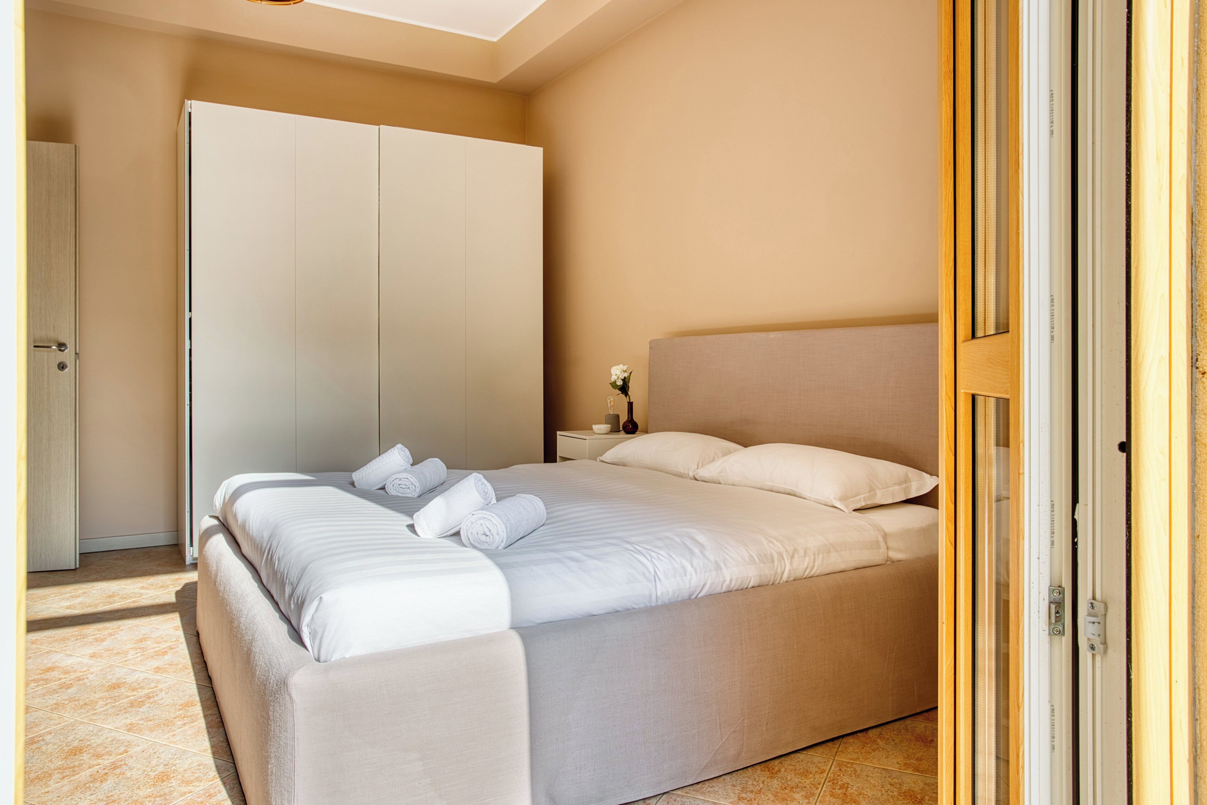 Une chambre à coucher avec un lit, une armoire et une table de chevet sur laquelle se trouve un vase.