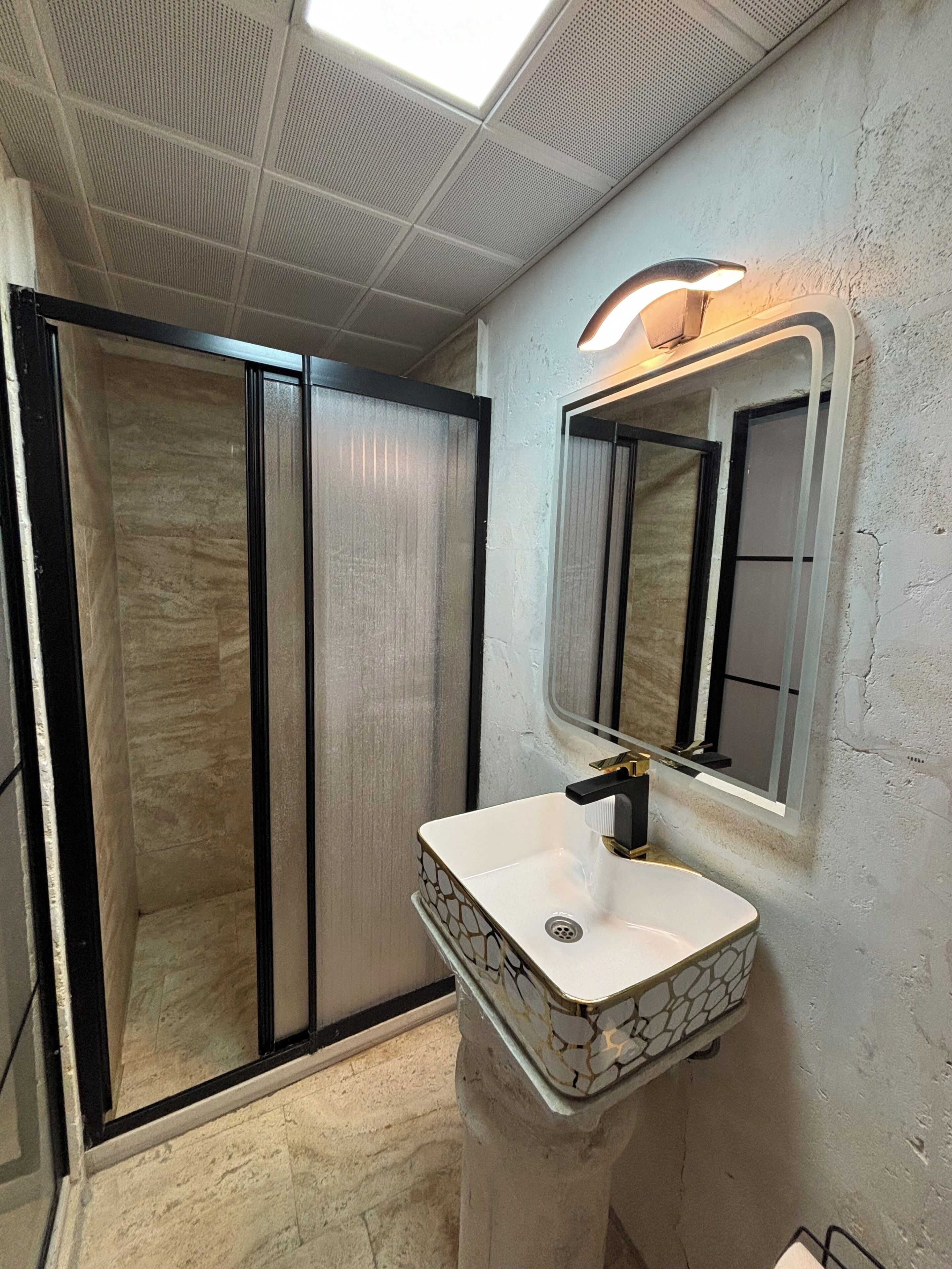A bathroom with a shower, a sink, and a mirror.
