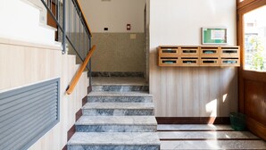 A staircase with marble steps, wooden handrails, and a wall-mounted mailbox.