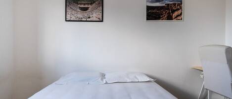 Ein Hotelzimmer mit einem Bett, einem Sessel und zwei gerahmten Bildern an der Wand.