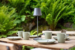 Een houten tafel met een lamp, borden en kopjes, klaar voor een maaltijd.