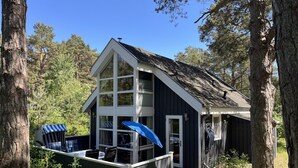 A cabin with a deck, a covered seating area, and a large window. - Holiday Home 'Strandpark Baabe' with Private Terrace and Wi-Fi (Baabe)