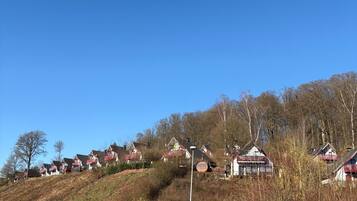 A road with houses on a hillside, a blue sign, and a metal guardrail.