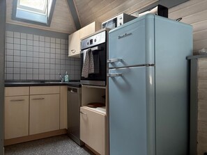 A kitchen with a light blue refrigerator, a built-in oven, and a window above the sink.