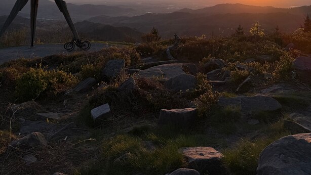 A tripod on a mountain with a sunset in the background.
