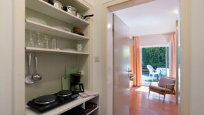 A kitchen with shelves, a coffee maker, and a dining area with a chair and table. - Holiday Apartment 'No. 9' with Mountain View and Balcony; additional dogs upon request (Bad Wildbad)