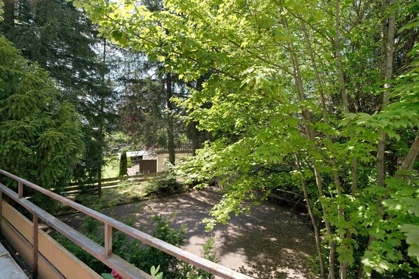 Un jardin avec une clôture en bois, un étang et divers arbres.