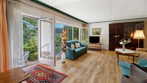A spacious living room with a sofa, a TV, and a dining area. - Holiday Apartment 'No. 10' with Mountain View and Private Terrace; additional dogs upon request (Bad Wildbad)