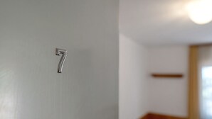 Lähikuva metallisesta numerosta ’7’, joka on kiinnitetty oveen ja joka osoittaa huoneen numeron.