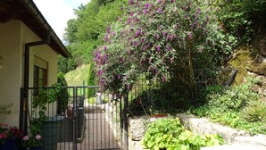 A garden with a gate, a building, and a stone wall. - Apartment 'Mühlengrün' with Mountain View, Balcony and Wi-Fi (Oberwolfach)