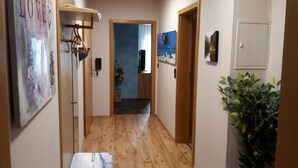 A hallway with wooden flooring, a door with a 'LOVE' sign, a blue wall, and a plant. - Apartment 'Mühlengrün' with Mountain View, Balcony and Wi-Fi (Oberwolfach)