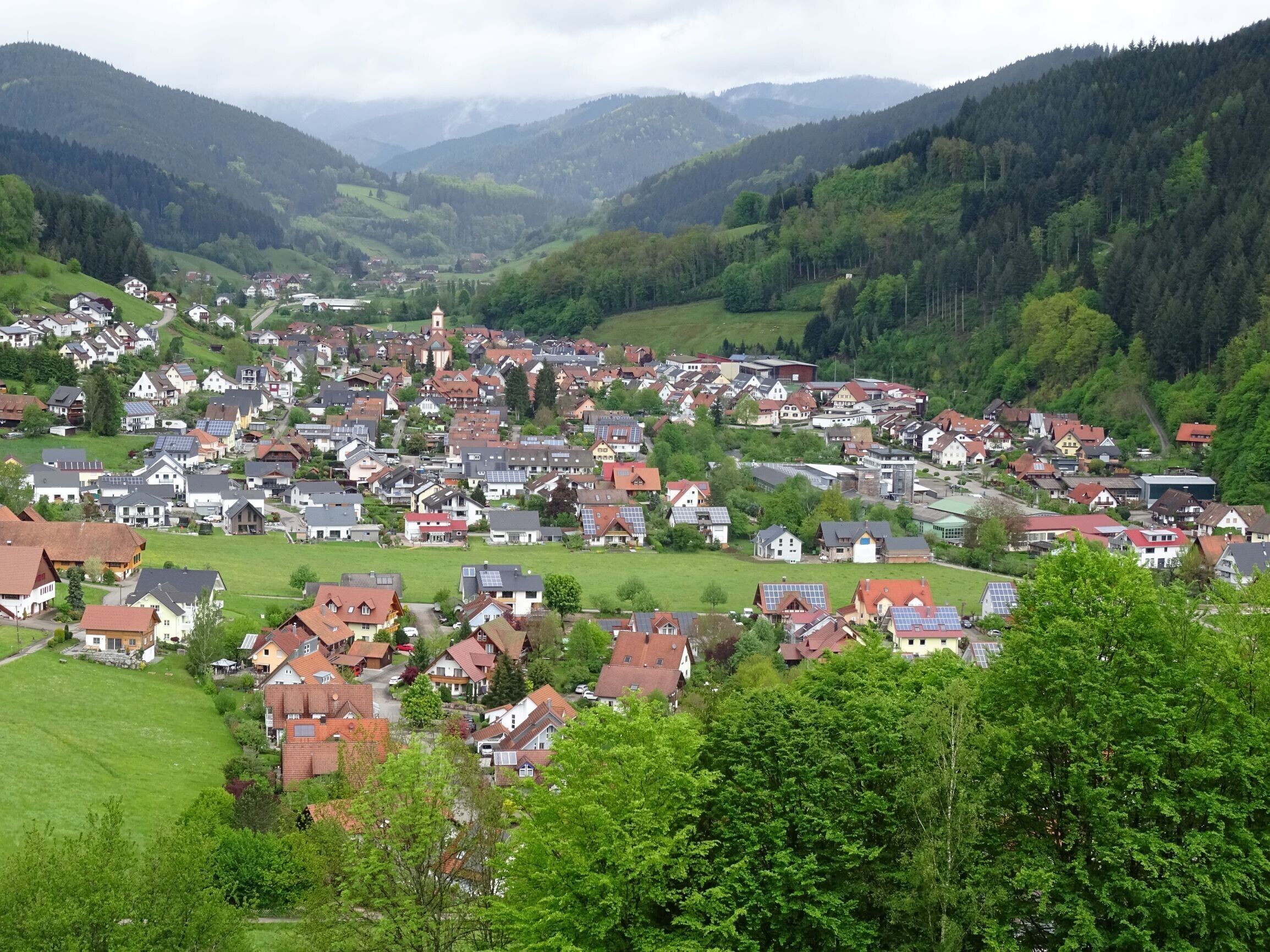 A town with houses, a church, and surrounding greenery.