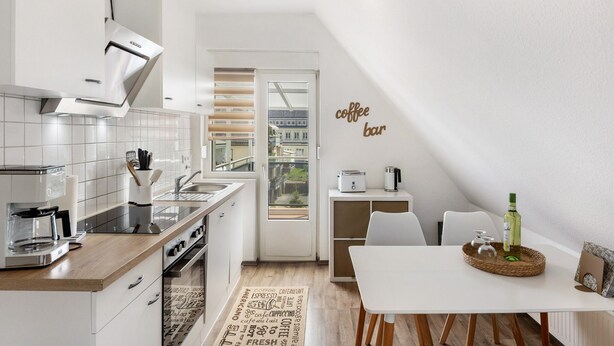 Eine moderne Küche mit einer Kaffeebar, einem Essbereich und Blick durch eine Glastür.