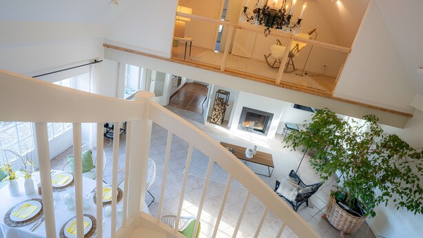 Un interior de varios niveles con una escalera, comedor y chimenea.