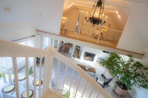 A multi-level interior with a staircase, dining area, and a fireplace.