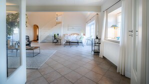 Amplia sala de estar con una escalera, una mesa de comedor con sillas y vistas al piso superior.