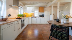 Una cocina con armarios blancos, una mesa de comedor de madera y una silla negra.