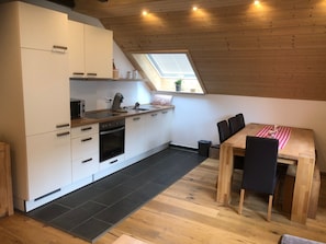 Eine moderne Küche mit weißen Schränken, einem Holzespeisetisch und einem Oberlicht.