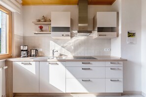 Eine moderne Küche mit weißen Schränken, Edelstahlgeräten und einem Fenster für natürliches Licht.