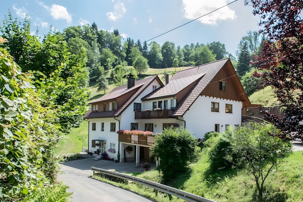 Une maison à deux étages avec un toit en pente, un balcon et un petit porche.
